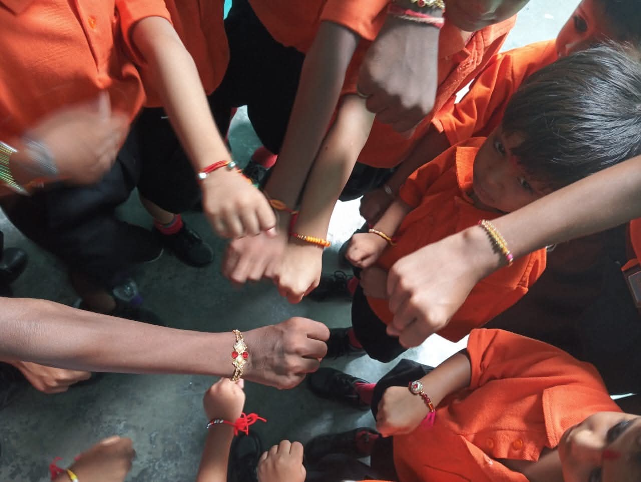 School children showing Rakhi threads on their wrists in classroom uniform